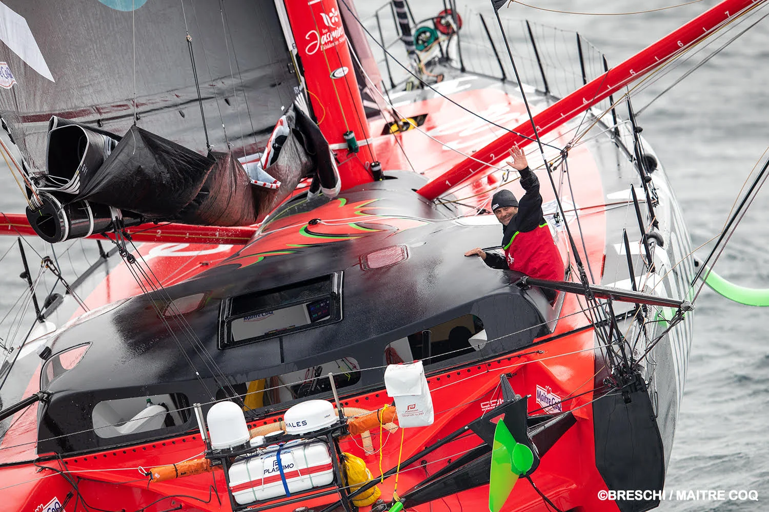 Yannick Bestaven sur son IMOCA Maître Coq en navigation, salue l'objectif