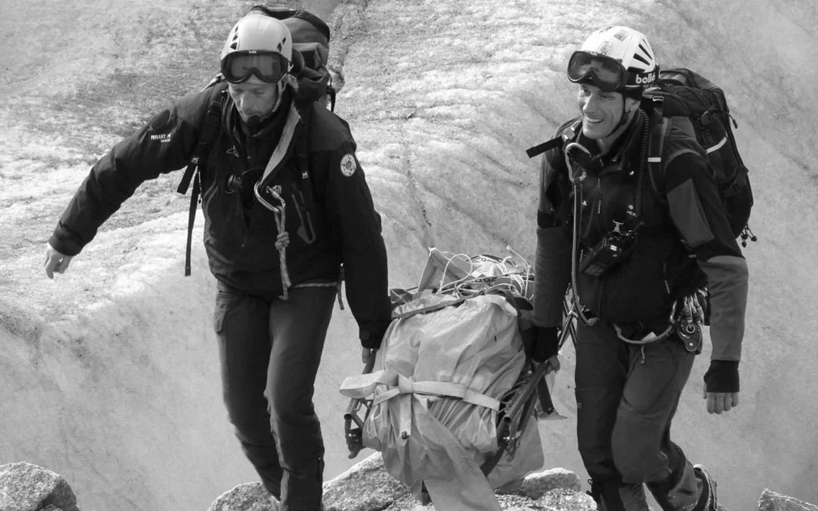 eric mesnier porte un lourd matériel avec un collègue en intervention. Sac à dos, casque, combi, harnais, et portent à 2 je pense une civière pliée.