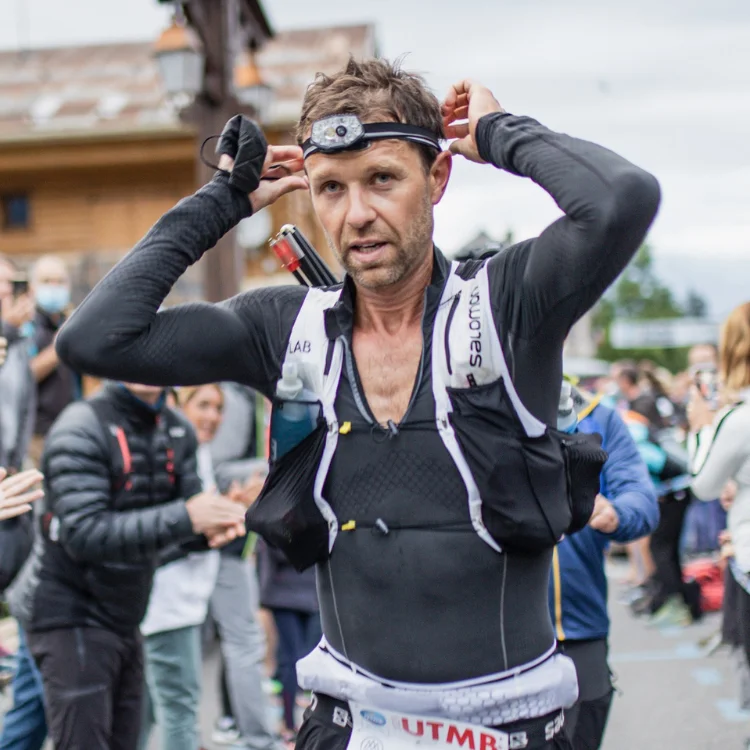 François d'Haene ajuste sa frontale en pleine course ultratrail, avec public qui l'applaudit au passage