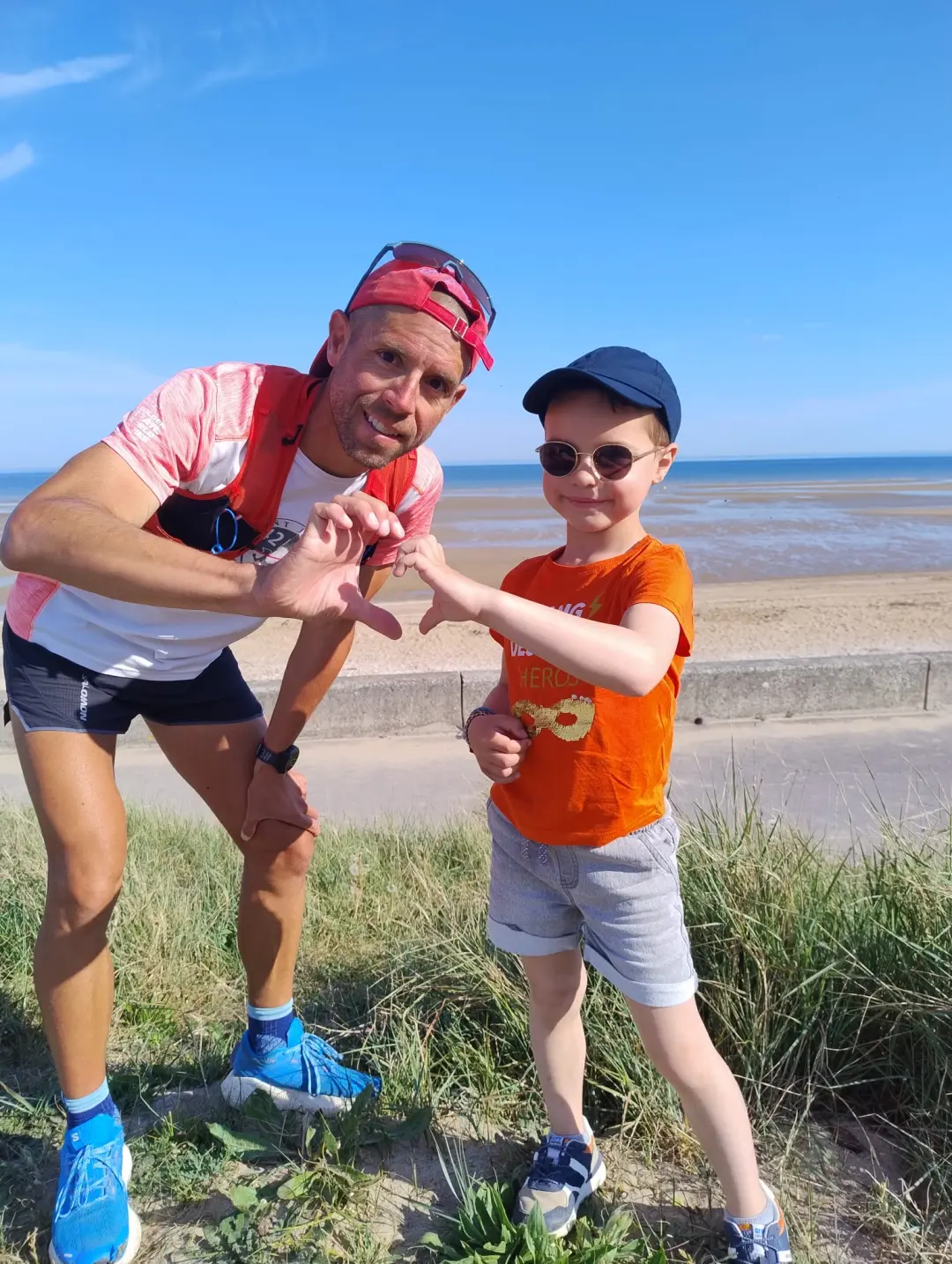 paul fontaine en tenue de course, fait un demi-coeur avec un petit garçon faisant l'autre moitié avec ses doigts