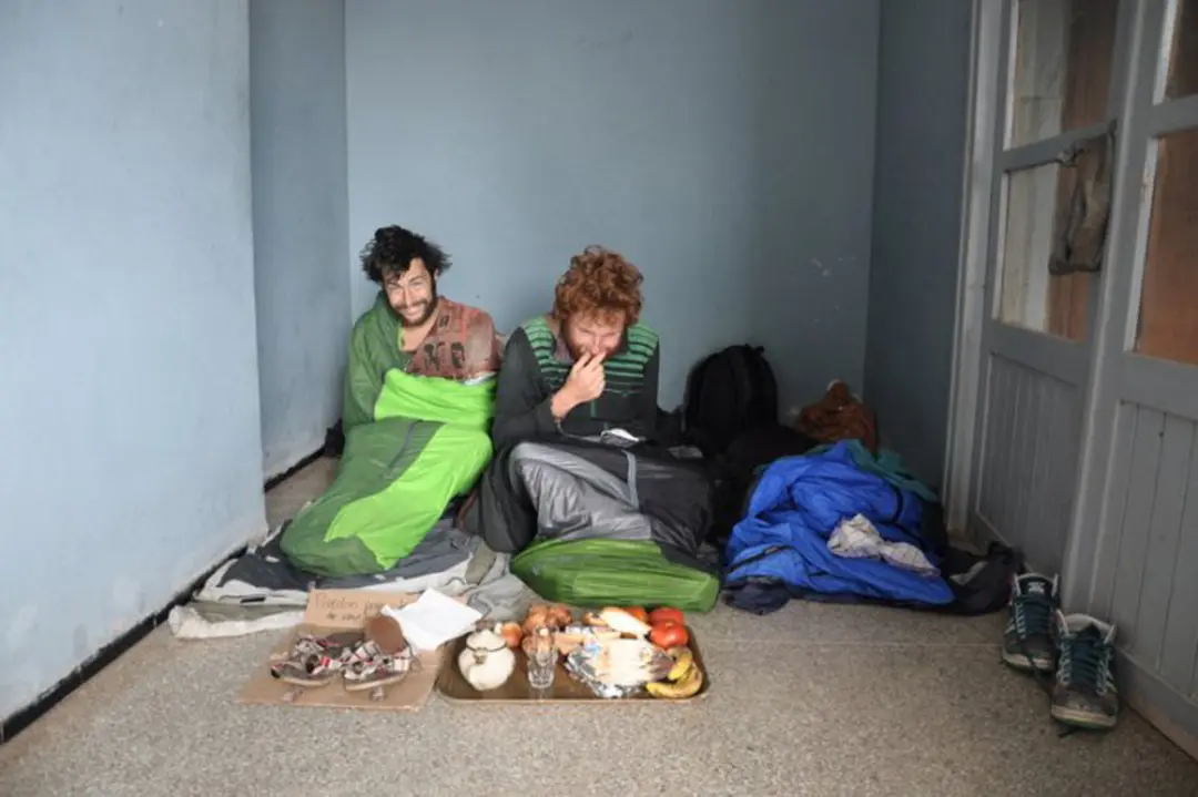 les 3 amis se réveillent dans un squat improvisé, ils sont assis dans leurs sacs de couchage à même le sol